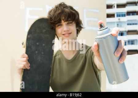 Teen boy holding barattolo di vernice spray, sorridente in telecamera Foto Stock