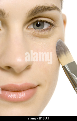 Donna di applicare il make-up a guancia, sorridente in telecamera, close-up Foto Stock