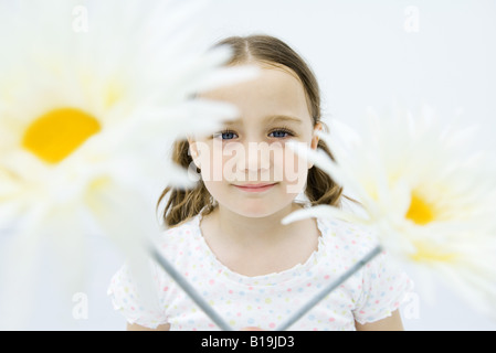 Ragazza dietro i fiori, sorridente in telecamera, ritratto Foto Stock