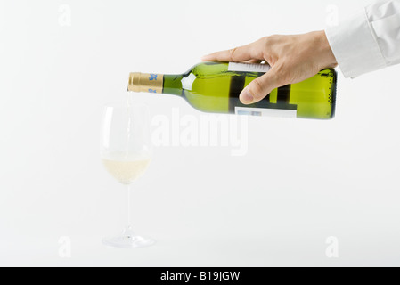 Mano d'uomo versando il vino bianco in vetro, vista ritagliata Foto Stock