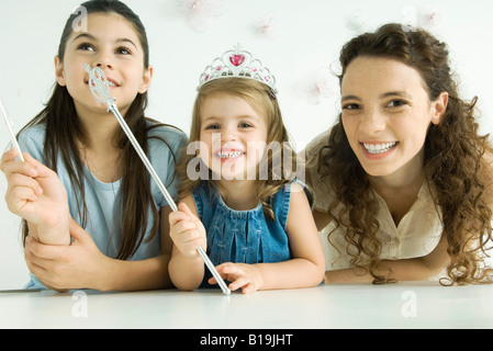 La madre e le sue due figlie, sorridente in telecamera, più giovane ragazza che indossa tiara e tenendo la bacchetta Foto Stock
