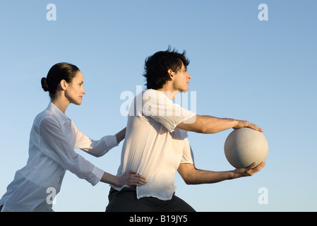 Coppia insieme all'aperto, uomo tenendo palla, donna uomo di contenimento di hips Foto Stock