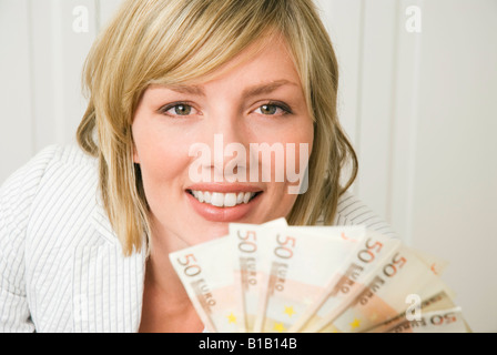 Donna che mantiene 50 le banconote in euro, sorridente, ritratto Foto Stock
