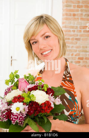 Giovane donna holding mazzo di fiori, ritratto, close-up Foto Stock