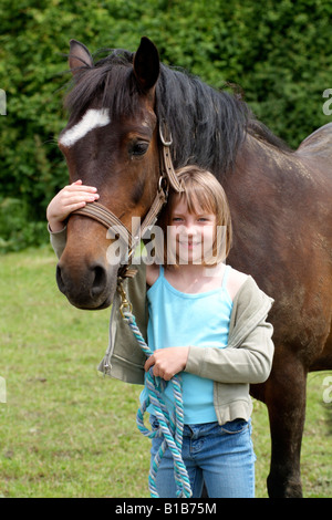 Bambina mentre tiene il suo pony dal rein nel paddock Foto Stock