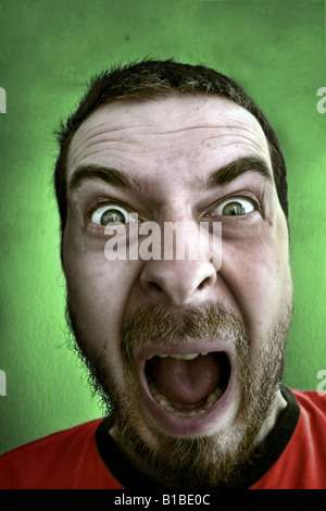 Urlando volto di scioccato funny uomo isolato su verde Foto Stock