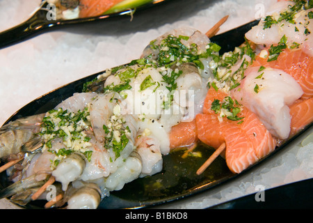 Una piastra con barbecue spiedini di pesce con misto di pesce merluzzo salmone e gamberetti e spezie in un vassoio pronto per il grill Foto Stock