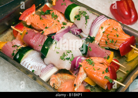 Frutti di mare barbecue spiedini con misto di pesce Salmone merluzzo tonno cetriolo cipolla e spezie in un vassoio pronto per il grill Foto Stock