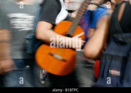 Chitarrista strumento portante in folla in strada in città Foto Stock