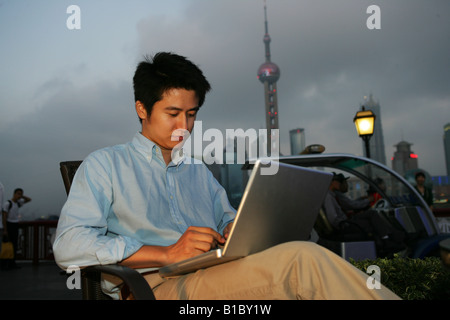 Giovane uomo utilizzando laptop tabella accanto al Bund,Shanghai, Cina Foto Stock