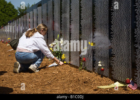 I familiari dei caduti della guerra del Vietnam mettere fiori vicino ai nomi del viaggiare memorial wall Foto Stock