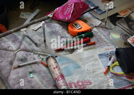 Siringhe su un materasso sporco in casa di un eroinomane. Foto Stock