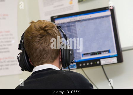 Bambino che indossa gli auricolari durante una lezione di lingua presso una scuola del Regno Unito Foto Stock