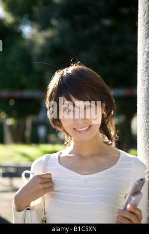 Giovane donna tenendo il telefono cellulare Foto Stock