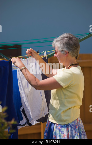 Signora appendere fuori il lavaggio a secco Foto Stock