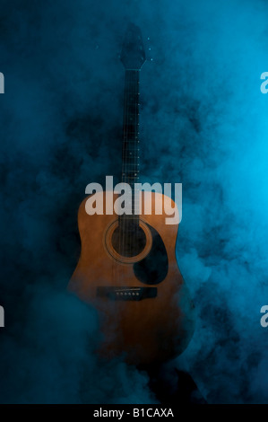 Chitarra acustica in fumo e stadio della luce ambiente Foto Stock