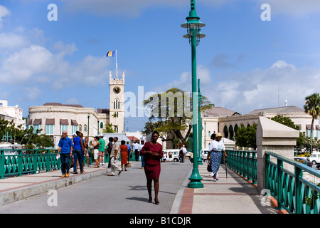 Le persone camminare su un ponte il palazzo del parlamento in background Bridgetown Barbados Caraibi Foto Stock