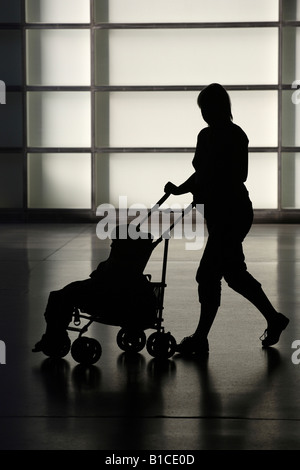 Silhouette di una donna in stato di gravidanza spingendo un contenuto della PRAM Foto Stock