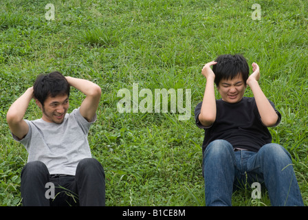 Due giovani uomini facendo sit ups Foto Stock