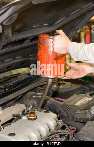 Mechanic rifornimento coppa dell'olio durante un'automobile cambio dell'olio Foto Stock