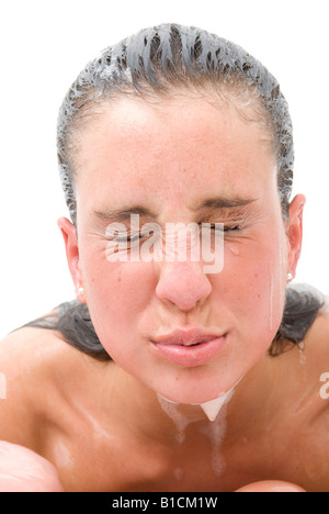 Giovane donna avente una vasca da bagno, strizzare gli occhi come acqua è in esecuzione oltre il suo volto Foto Stock