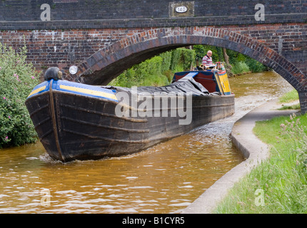 Vecchie vie navigabili britannico di lavoro barca stretta on Trent & Mersey Canal passando sotto il ponte vicino Rode Heath Cheshire England Regno Unito Foto Stock