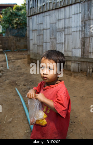 Un piccolo ragazzo dalla tribù Lisu nel nord della Thailandia con il cibo ha appena acquistato da un prodotto alimentare venditore ambulante Foto Stock