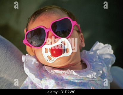 A due settimane vecchio bambina indossa gli occhiali da sole e succhiare un succhietto Foto Stock