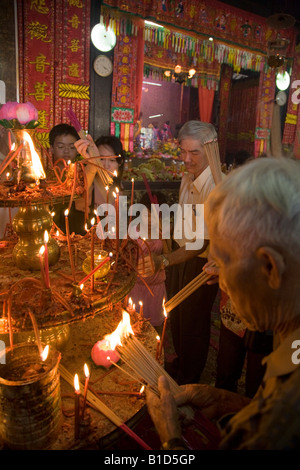 Adoratore maschio tempio di illuminazione candele presso il Tempio della Dea della Misericordia, durante il Capodanno cinese. Georgetown. Penang. Malaysia. Foto Stock