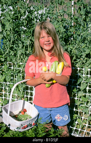 USA OREGON una giovane ragazza di fattoria detiene squash i pomodori e i piselli a scatto appena raccolto da un giardino di casa Foto Stock