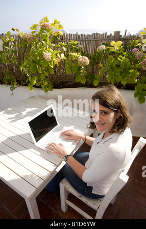 Giovane donna writting sul suo laptop macbook in una terrazza mediterranea in Casapueblo Punta del Este Uruguay Foto Stock