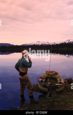 Flyfisherman avente il caffè al mattino sul litorale di McBride lago vicino Lago Morice BC Foto Stock