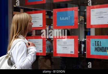 Donna in cerca di un lavoro o di cambiamento di carriera Posti vacanti pubblicizzato nella finestra di agenzia di reclutamento locali la ricerca di lavoro Foto Stock