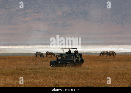 I turisti in sommità aperta jeep safari fotografando la fauna selvatica nel cratere di Ngorongoro, Tanzania Africa Foto Stock