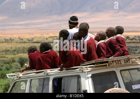 Gruppo di Africano nero scolari di safari nella sommità aperta in jeep del cratere di Ngorongoro, Tanzania Africa Foto Stock