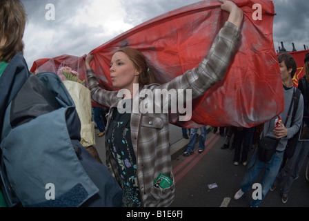 Donna marcher porta grande bandiera rossa svoltasi a le braccia sopra la testa in anti-guerra in marzo a Londra. Foto Stock