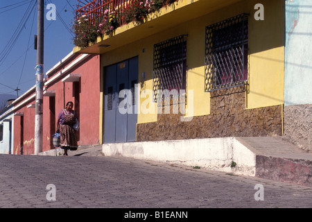 Donna che trasportano shopping bag a piedi giù per una strada nella città di Quetzaltenango, Guatemala Foto Stock