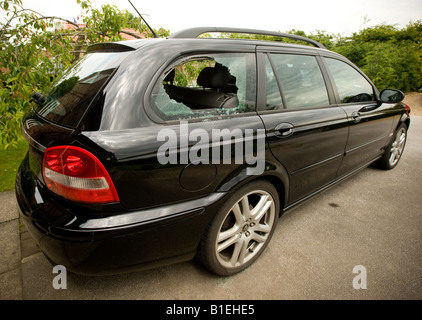 Finestrino fisso posteriore rotto di una Jaguar nera parcheggiata su una strada di York dopo un rodaggio. Foto Stock