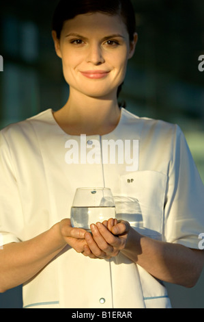 Ritratto di una giovane donna con in mano un bicchiere di acqua e sorridente Foto Stock
