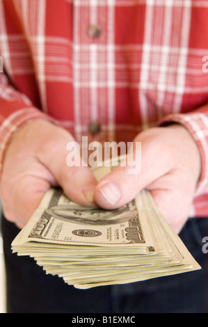 Close up di un uomo con le mani in mano una catasta di centinaia di fatture del dollaro. Foto Stock