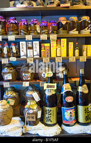 Bottiglie di Sake sul display in uno dei molti turisti in negozi di souvenir Sul Kokusai Dōri Street a Naha, Okinawa, in Giappone Foto Stock