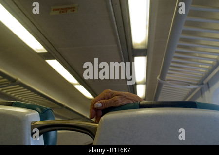 Donna anziana s appoggia la mano sul sedile indietro la ferrovia di Long Island Foto Stock