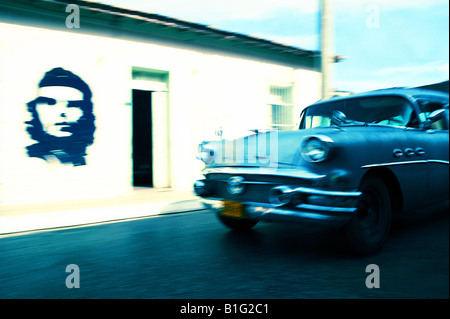 Vecchia vettura americana passando Che Guevera murale su una parete in Trinidad, Cuba Foto Stock