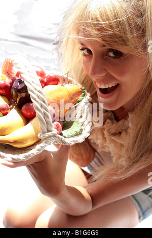 Vista aerea di una donna sorridente e tenendo un cesto di frutta Foto Stock