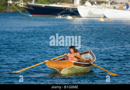 Una donna righe una tradizionale barca a remi attraverso English Harbour in Antigua. Foto Stock