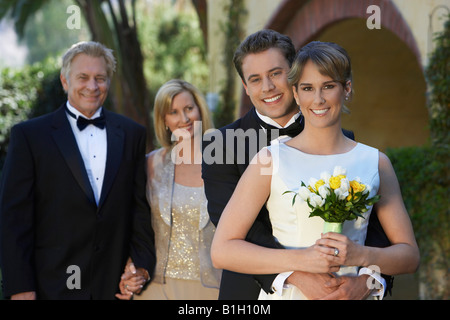 Sposa e lo sposo con i genitori in background, ritratto Foto Stock