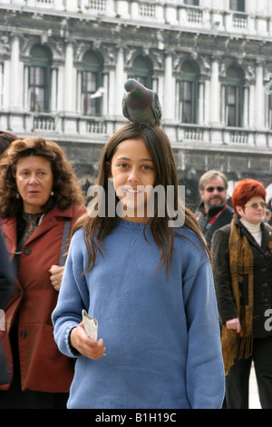 Una giovane ragazza con un piccione sulla sua testa, Piazza San Marco, Venezia, Italia Foto Stock