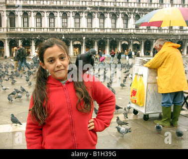 Una giovane ragazza alimenta i piccioni in Piazza San Marco, Venezia, Italia Foto Stock