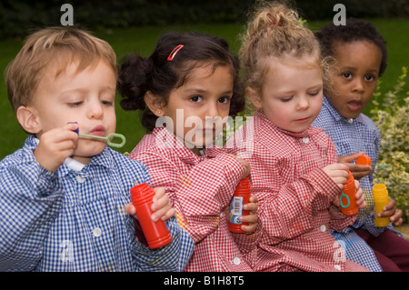 I bambini presso un privato scuola infantile giocando con bolle Foto Stock