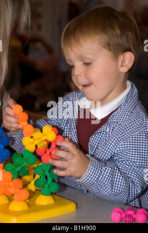 Giovani schoolboy giocare con un giocattolo di costruzione Foto Stock